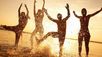 Sunset silhouettes sunlight dancing fun splashes beach wallpaper